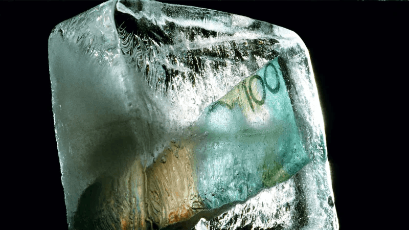 image shows Australian currency in form of a one hundred dollar note enclosed in a block of advice, portraying investment funds frozen frm access