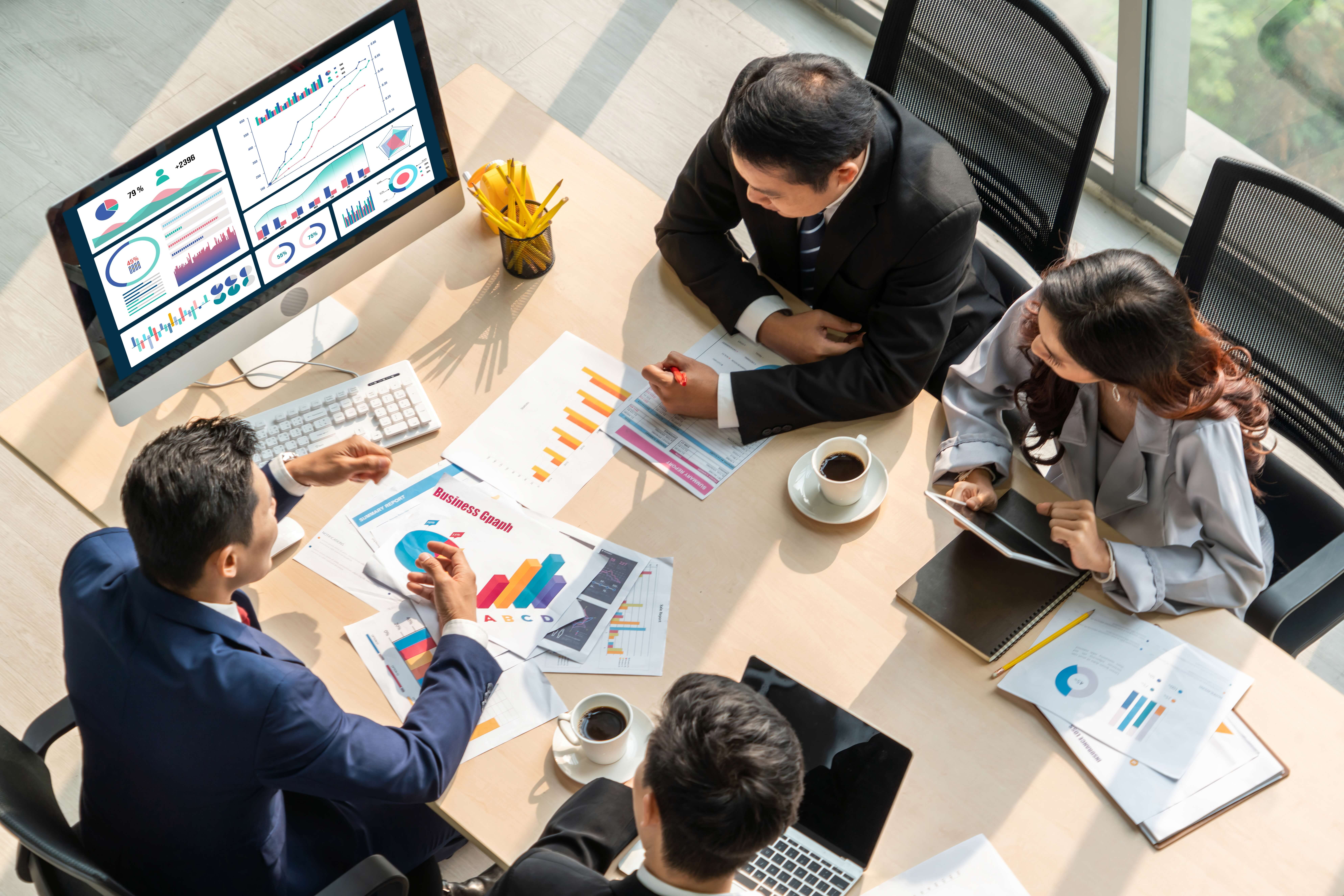 table with four people consulting at a computer and with charts and documents trying to resolve an SMSF Investment Strategy; to consider financial planning advice for employees