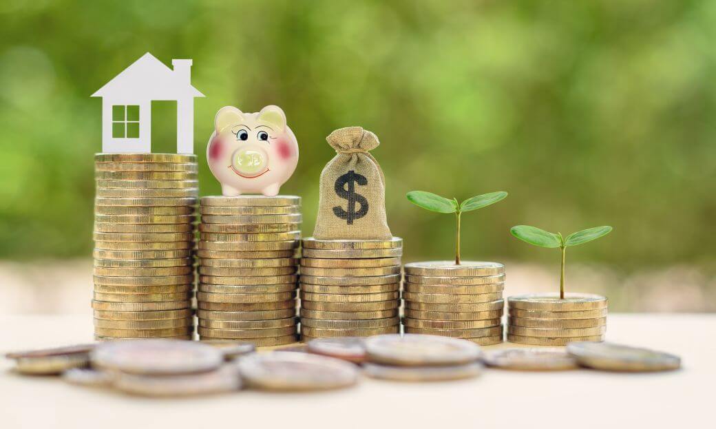 symbolising incremental wealth accumulatioon the image shows some loose money in the foreground with some stacks of coins behind showing that over time small accumulations grow and acn be invested in more and more substantial investments such as capital reserves, retirement savings, assets