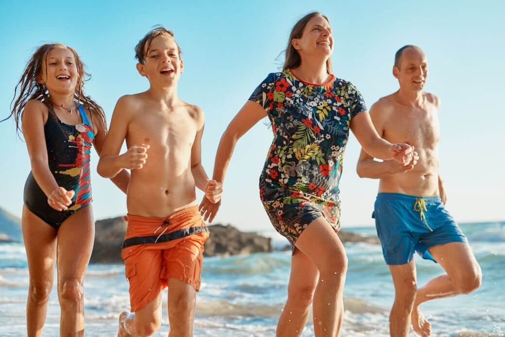 family group enjoying time together relaxed after the estate planning for their blended situation has been resolved as they frolick along a seashore
