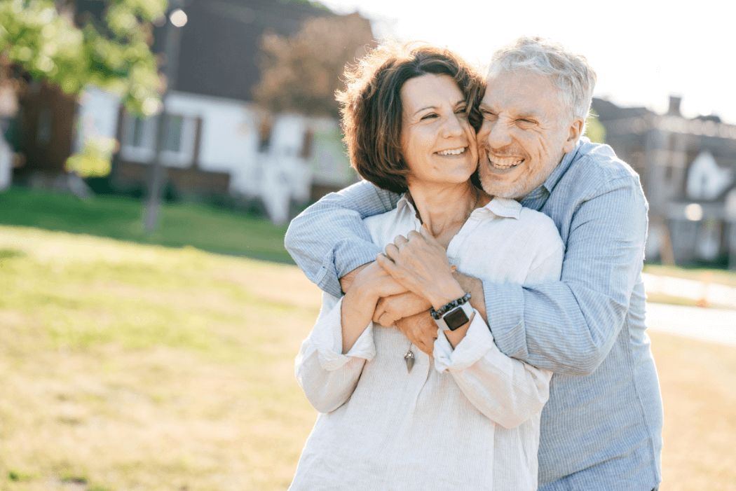 recently retired couple enjoying a smiling embrace as they show contentment with retirement lifestyle - perhaps reviewing the emerging Aged Care matters