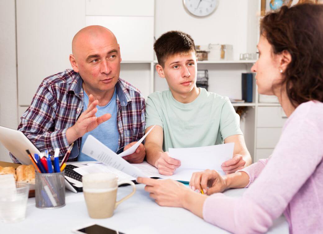 family of father, mother and young son gather at table to review preparation of family budget