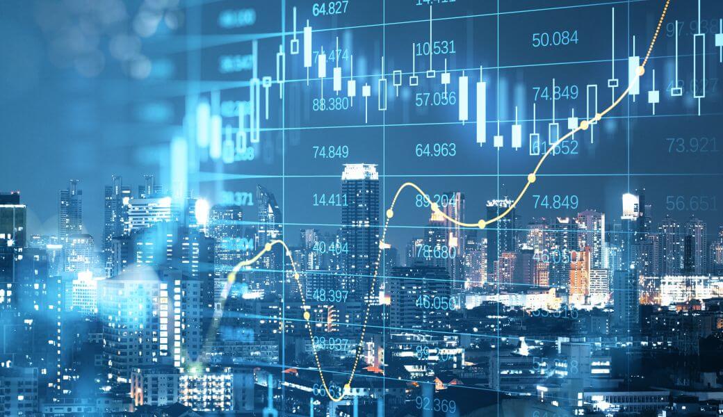 a sharemarket chart showing a steep decline, followed by a strong recovery overlays a night scene of a city - that chart showing how valuation declines precede recovery