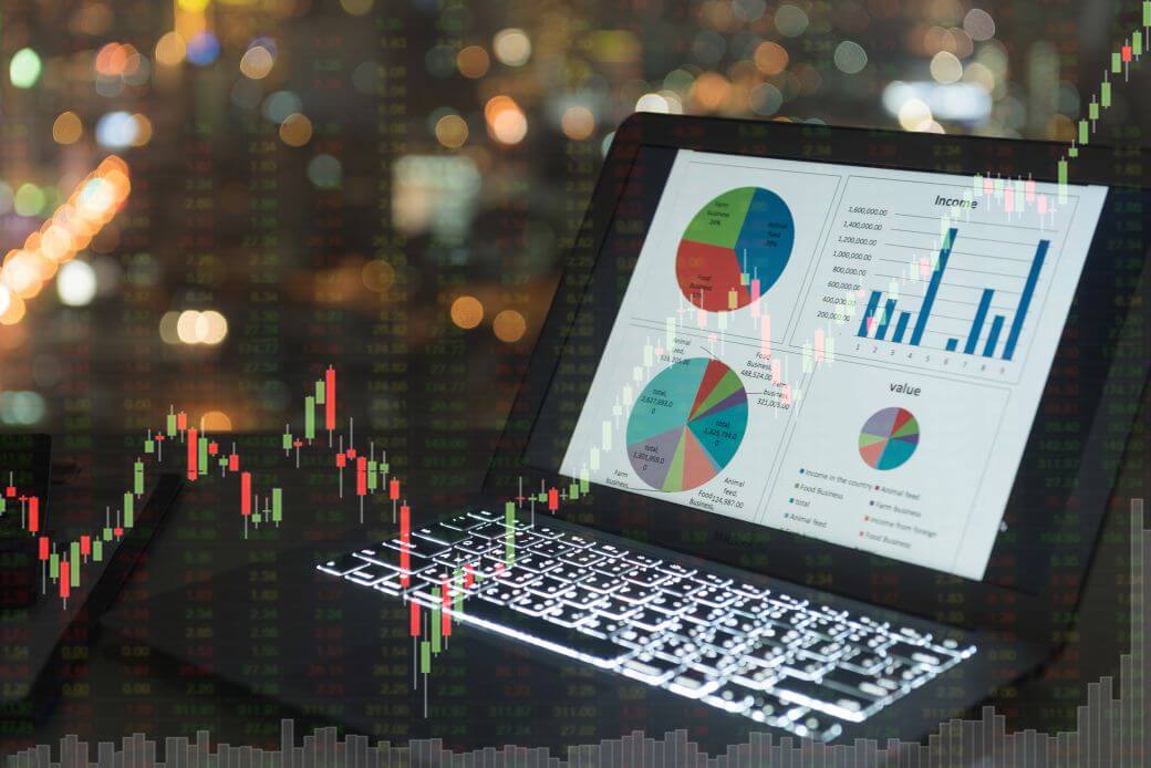 laptop open and with screen showing pie charts and graphs tracking investment costs and values in a search for investment yield: a chart overlays the image tracking investment performance of the portfolio