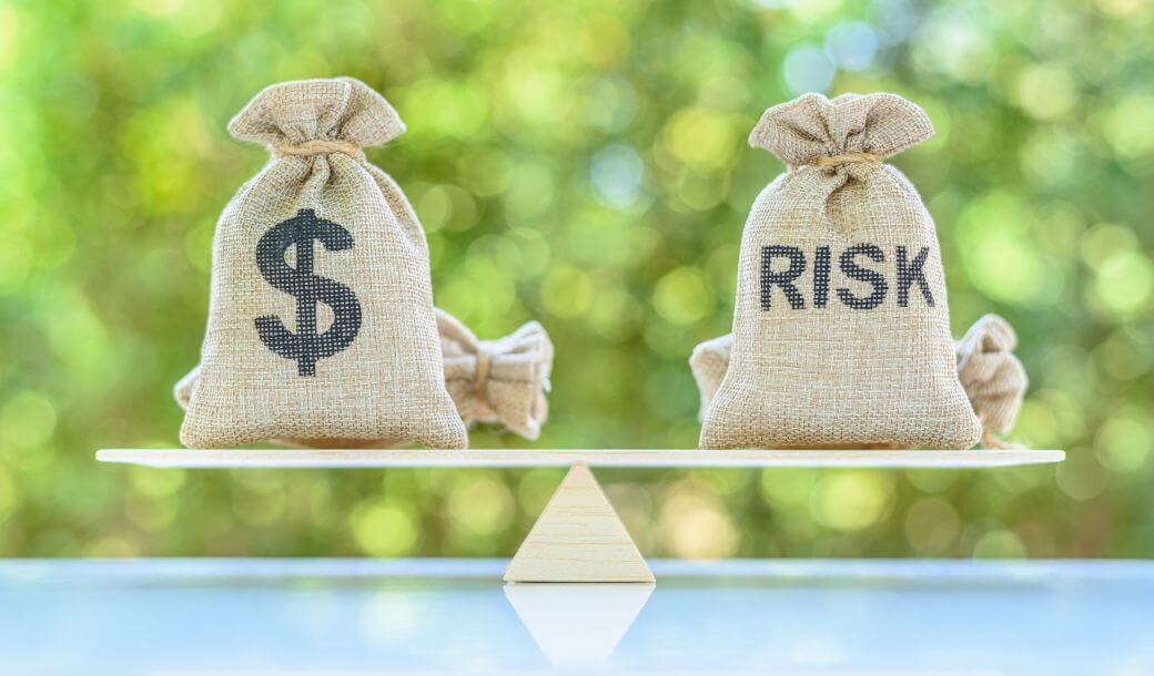 hessian money bags evenly balanced on a fulcrum, one displays a dollar sign, the other the word RISK - highlighting that cashflow is at risk when payment cycles are not honoured