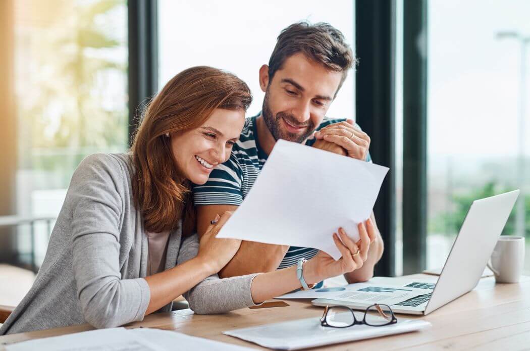 a young couple considering a plan presented for them to be retiring young - and they are both smiling, happy at the prospect of achieving that outcome