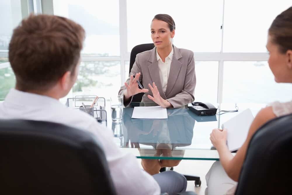 a female lawyer discussing issues with a client couple, having been referred by their financial adviser with whom they then liaise