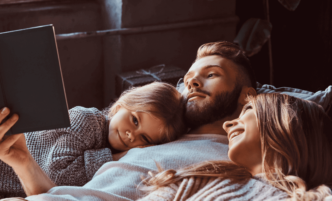 a couple are resting in bed, accompanied by their child: all are content with their situation in the knowledge that their estate planning has been completed and documented
