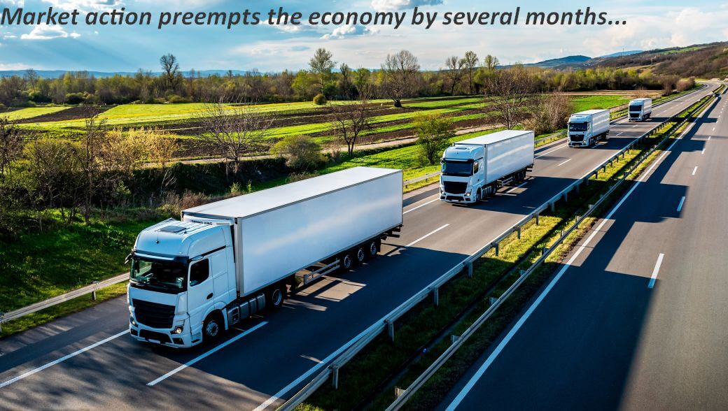 on a clear sunny day, four road fright trucks in convoy travel on a highway through fertile farmland; the market for goods preempt the strength of the economy