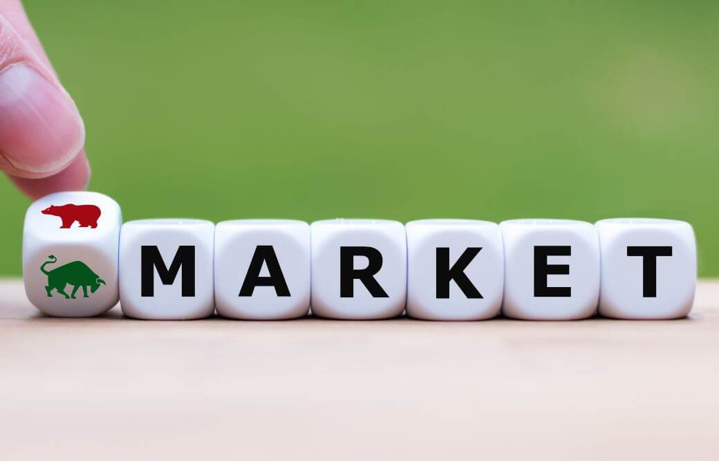 on a table surface with a green wall background, are a set of lettered dice blocks, the first showing at a tilt, one surface with the image of a bull and another with that of a bear: the rest of the dice spell out M-A-R-K-E-T. Shows the financial market influences can be quite strong