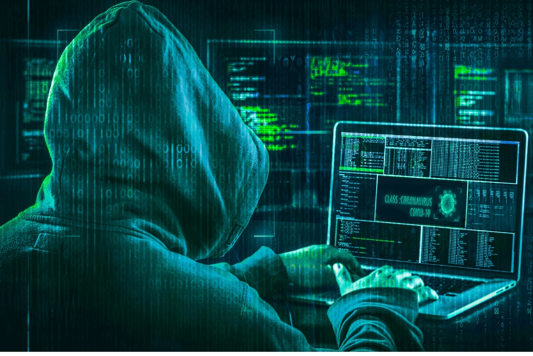 a hooded computer operator managing scam data, back to us and revealing a number of computer screens and a laptop as he works through potential victims to scam financially