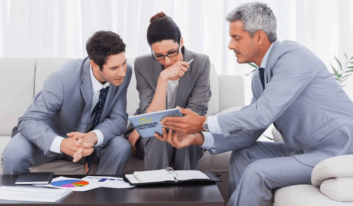 a client couple in a briefing session with their middle aged financial adviser undertaking a review of their financial plan