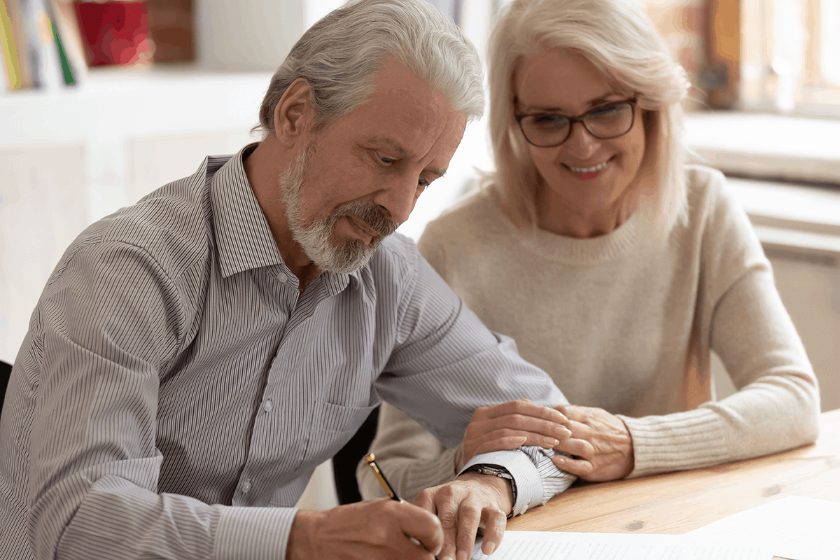 A senior couple enjoying the experience of signing their newly-prepared Wills, drafted with asset protection in mind