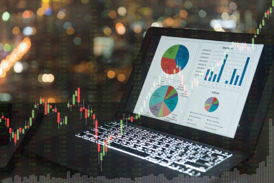 composite showing a laptop screen displaying pie and bar charts, overlaid with a candlestick chart in red and green indicating some investment market reflection