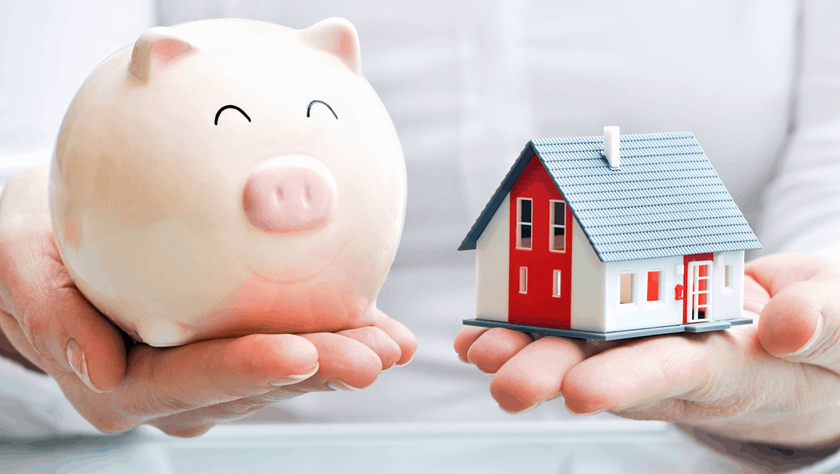 image shows a house being held in one hand and a piggy bank in the other indicating that this hoeowner has taken protection to secure home mortgage servicability