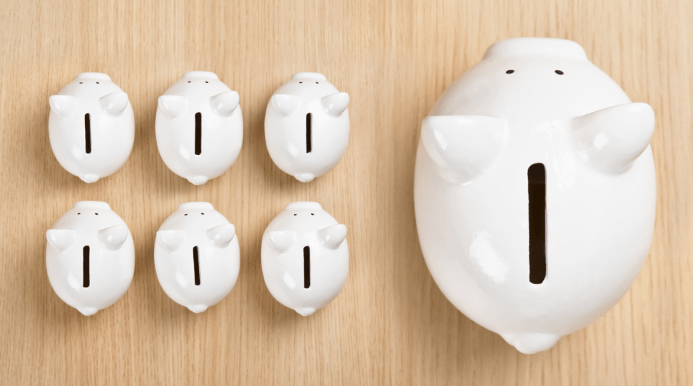 a collection of 6 small white piggybanks aside one large white piggybank standing on a woodgrain surface representing the savings and investment process - including superannuation investing