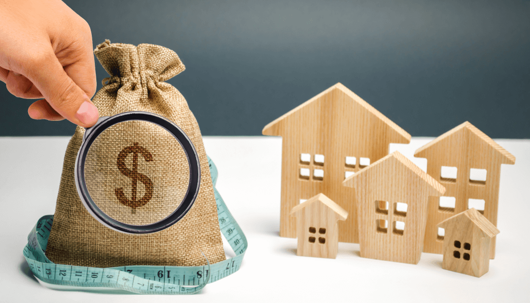 a hessian moneybag with a dollar sign overlaid with a magnifying glass examining the contents, alongside five cut out wooden houses as part of the asset base where capping superannuation funding is reviewed